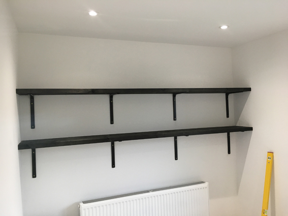 Chunky timber shelves, stained black, with black metal brackets fitted in home office