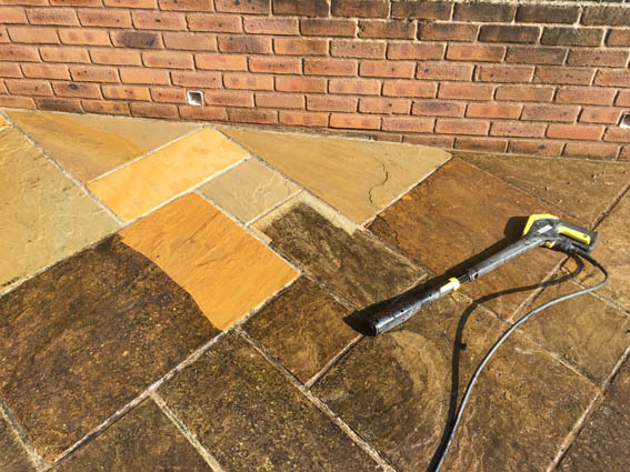 Indian sandstone paving and brick wall being cleaned with a Karcher K7 pressure washer
